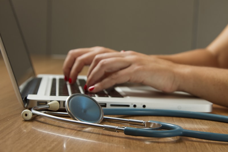 médico fazendo consulta online via notebook com estetoscópio ao lado